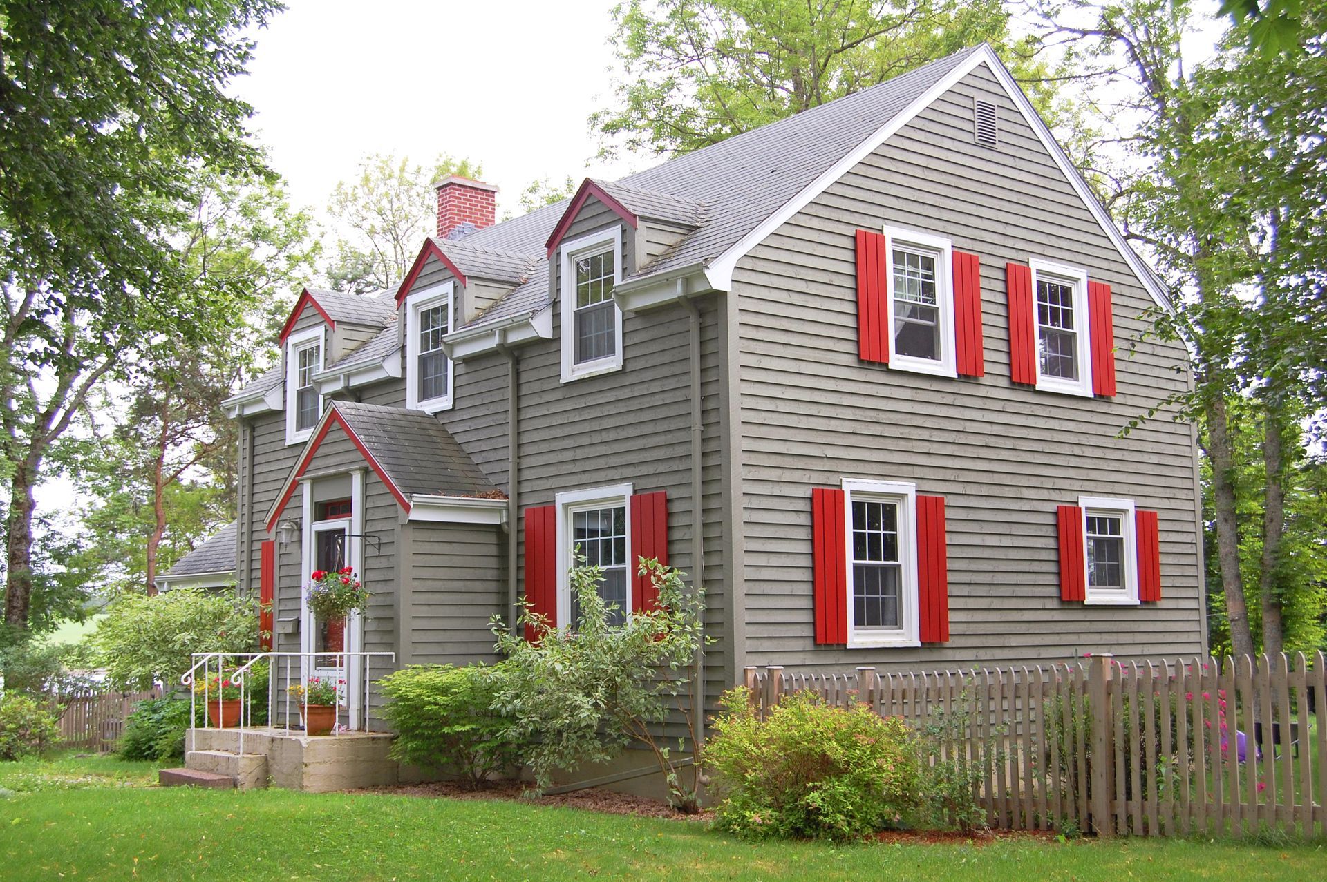 A grey house with red shutters on the windows