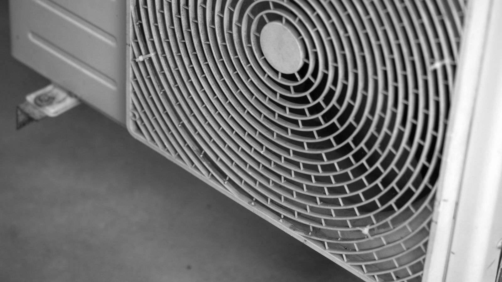 A black and white photo of a fan on a wall.