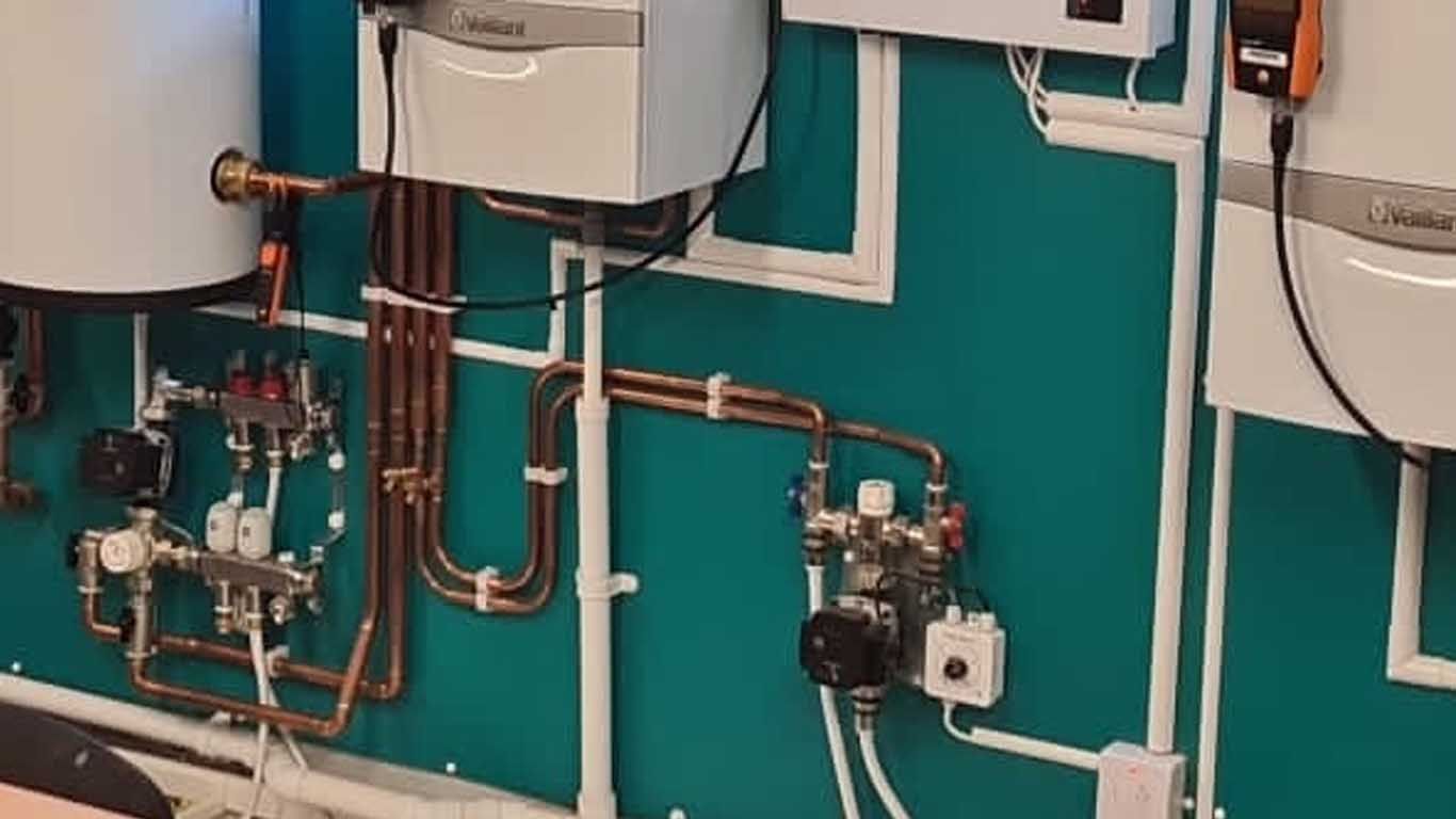 A wall with a lot of pipes and appliances on it.
