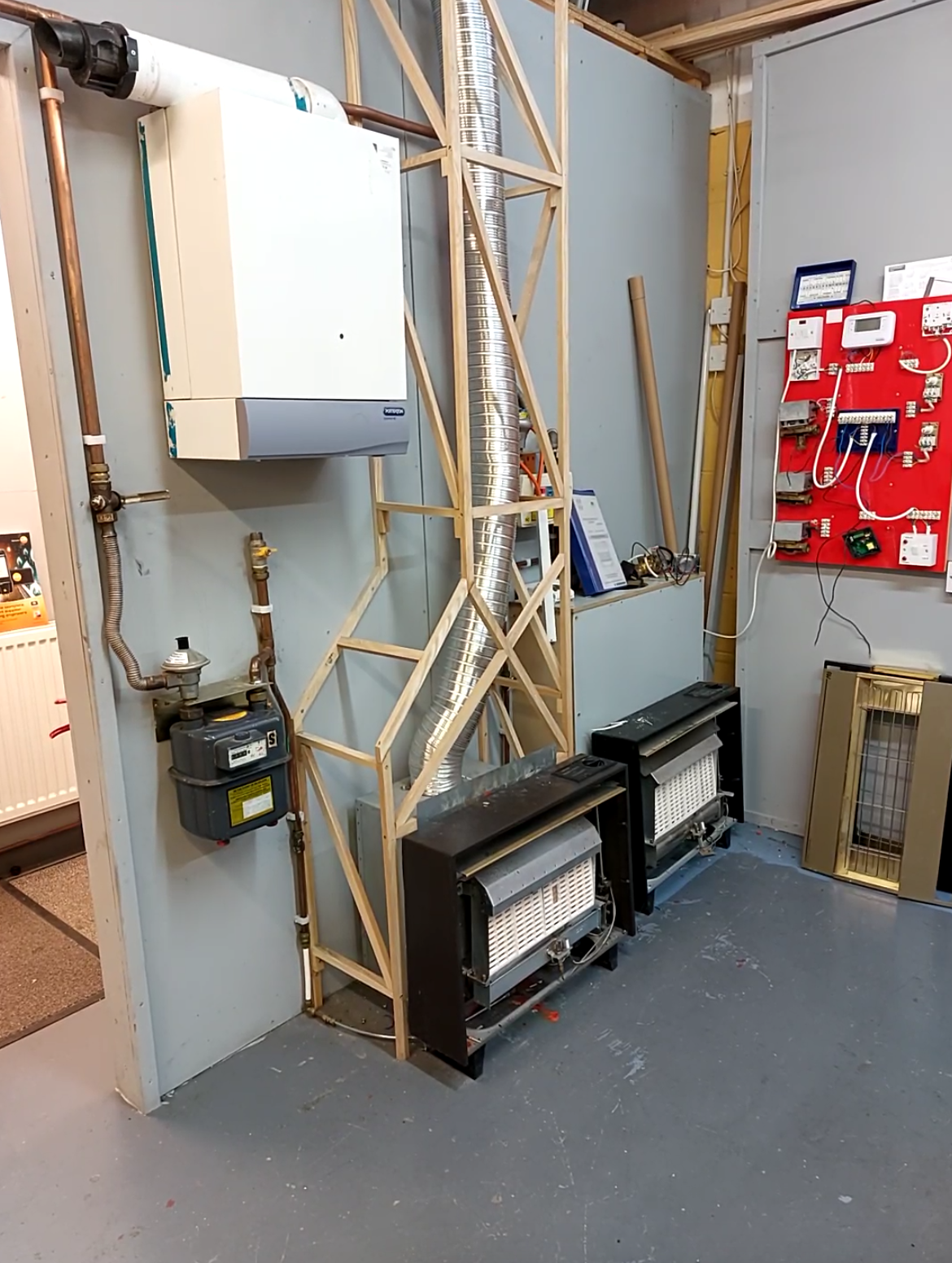 A room with a stove and a boiler on the wall.