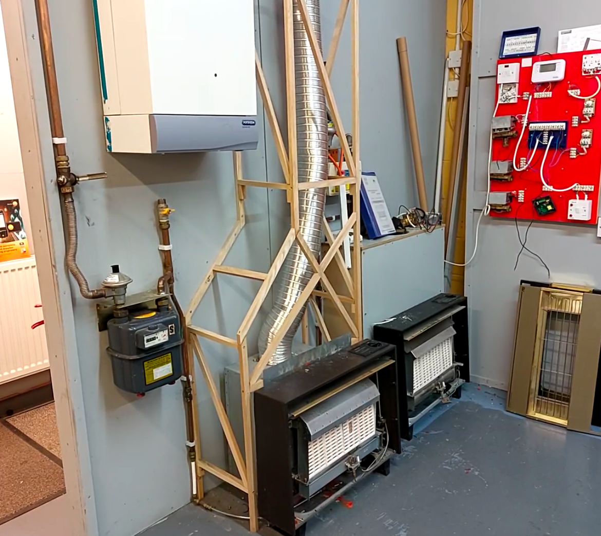 A room with a stove and a gas meter on the wall.