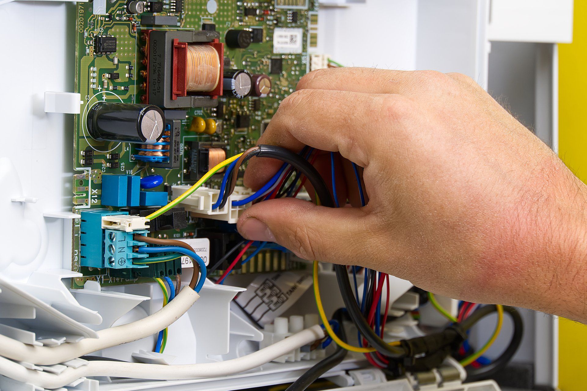 A person is working on a circuit board with wires.