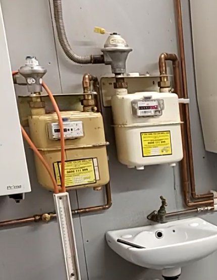 A bathroom with two gas meters and a sink