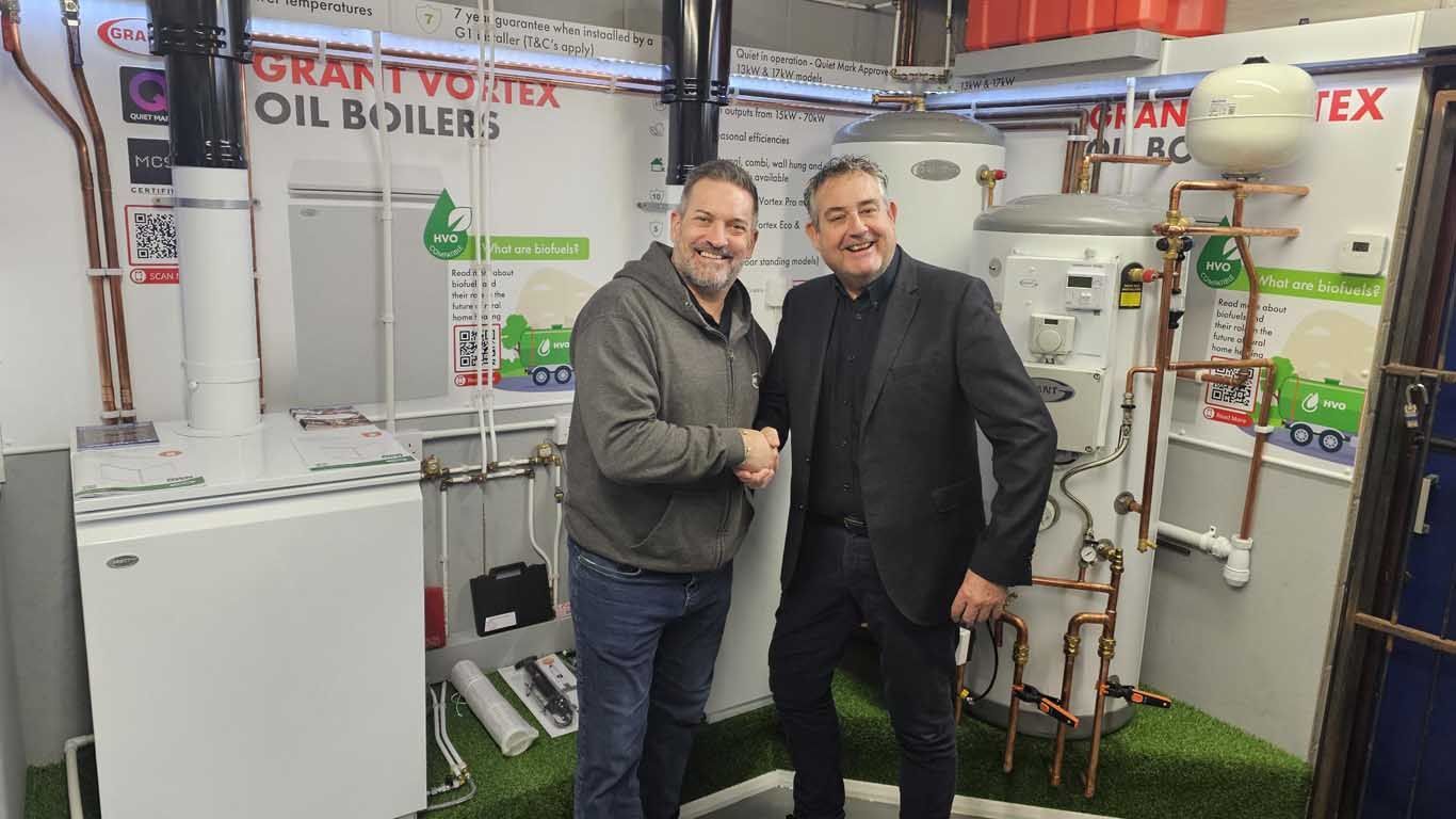 Two men are shaking hands in a room with water heaters.