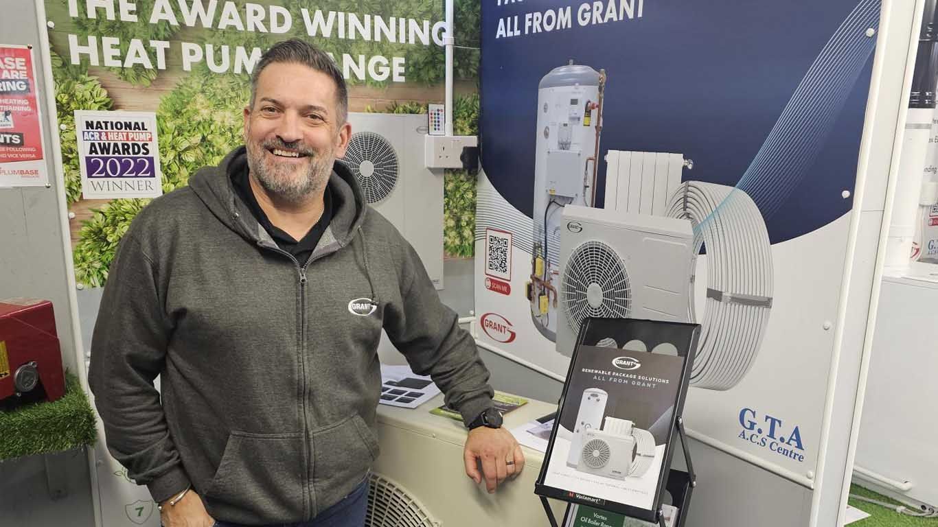 A man is standing in front of a sign that says `` the award winning heat pump ''.