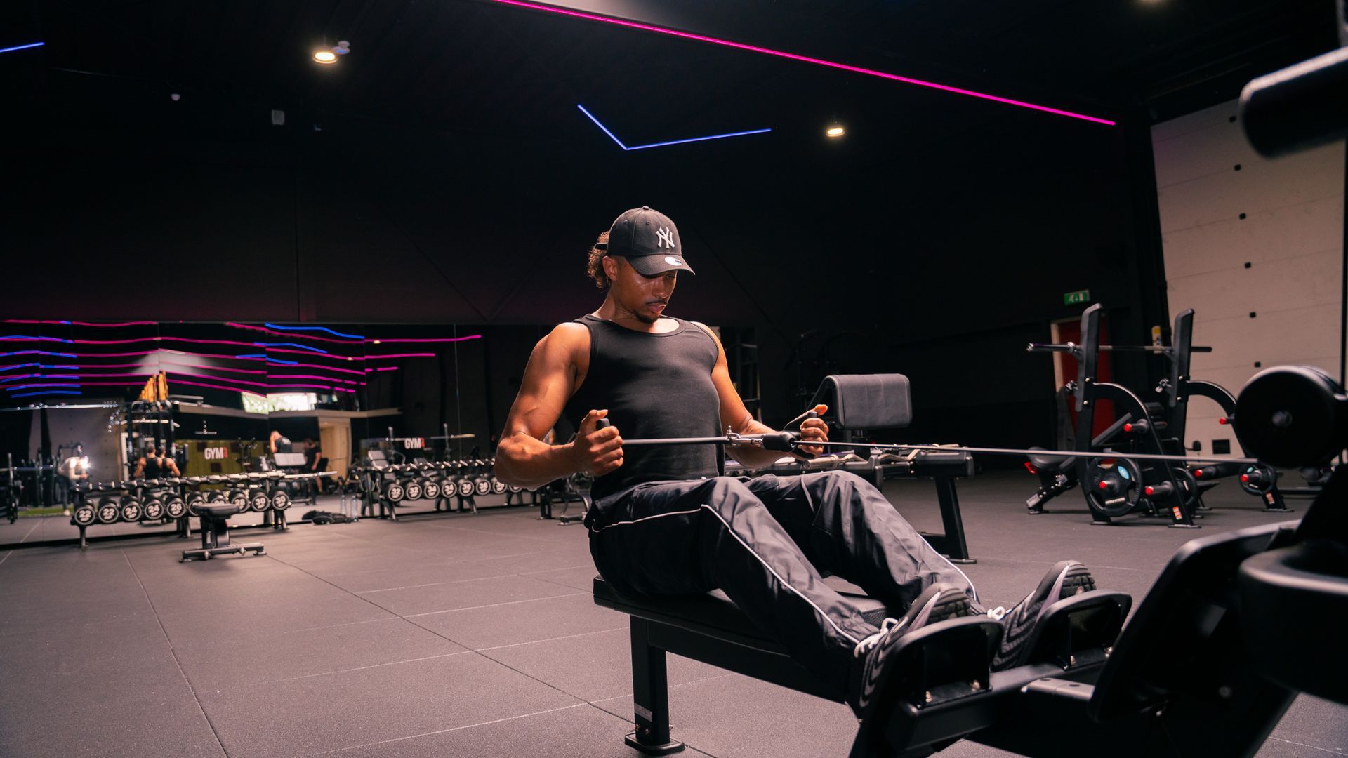 Dark, modern gym interior with weight machines and mirrors under dim lighting