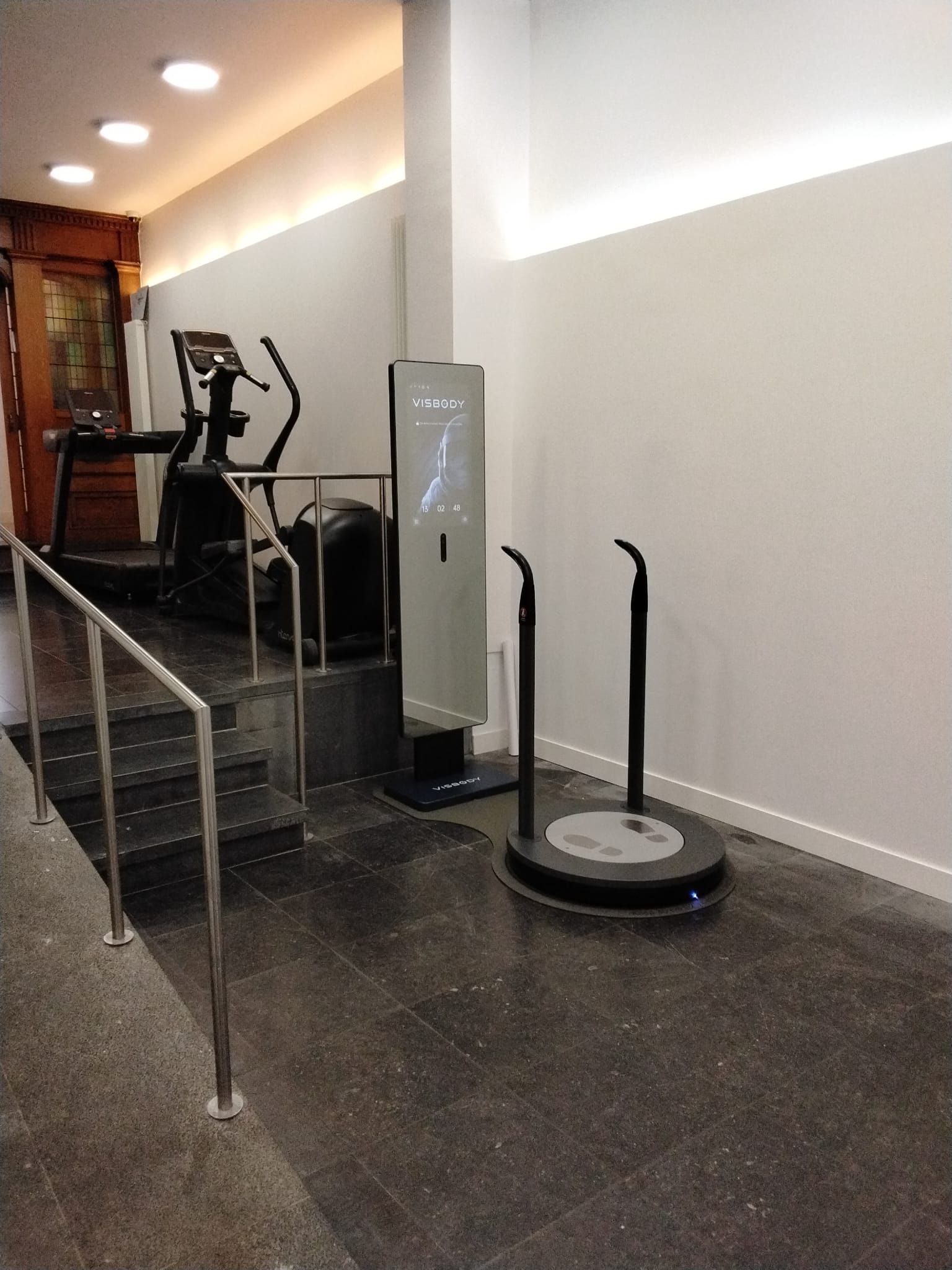 Hallway with a Visbody, and a polished black floor in a gym-like space