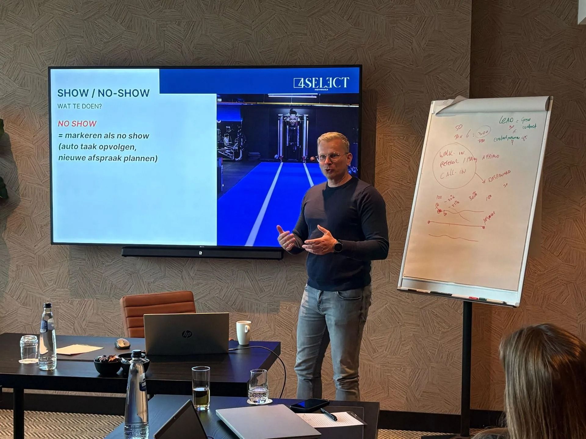 Presenter speaking beside slide screen and whiteboard in a meeting room