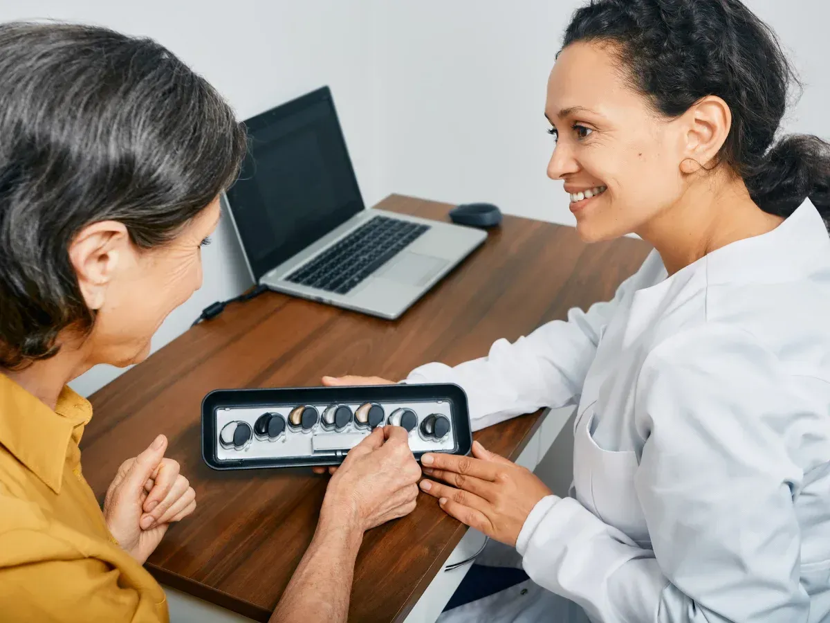 A hearing specialist and a patient testing a hearing aid model.