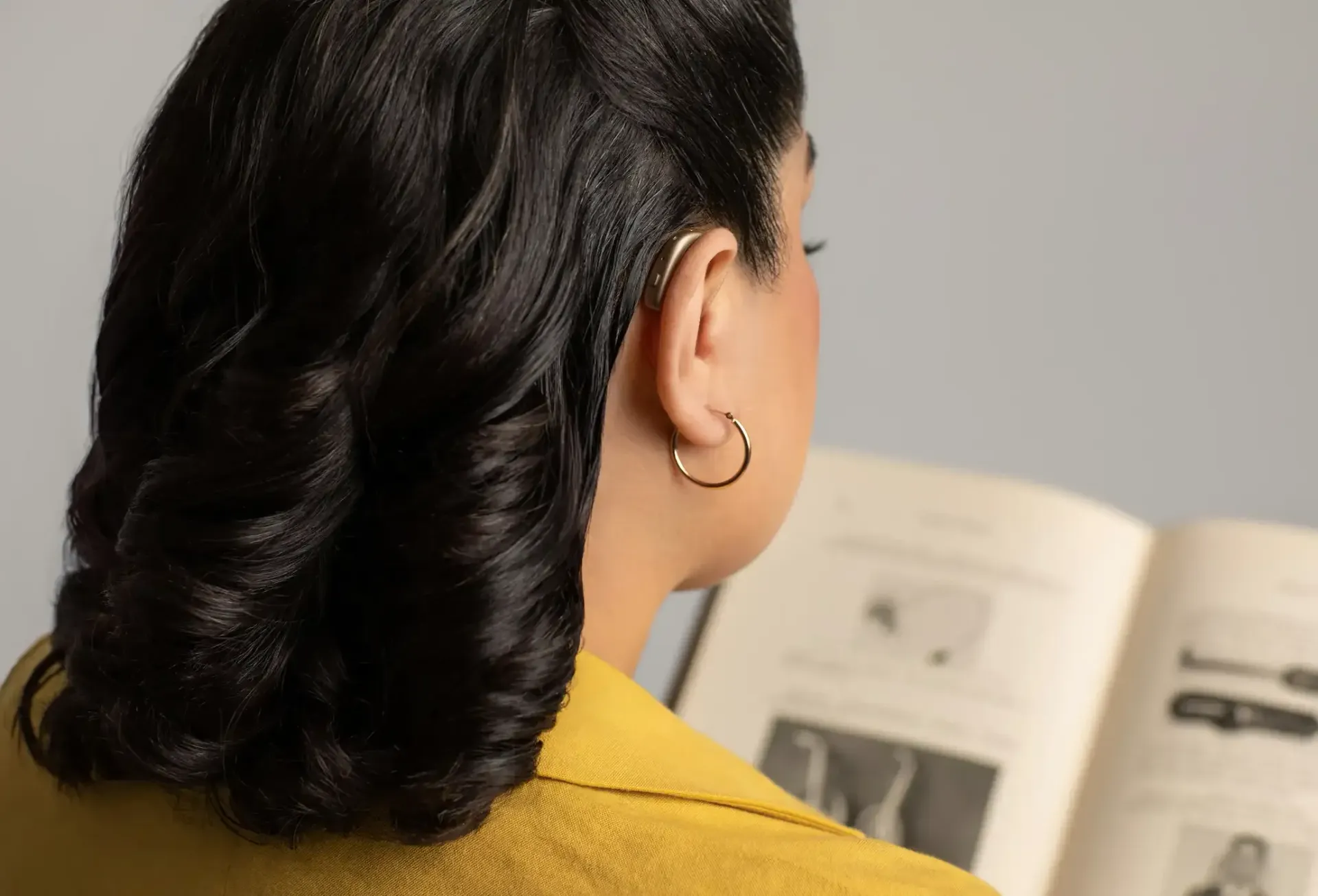 A woman wearing a basic behind-the-ear hearing aid.