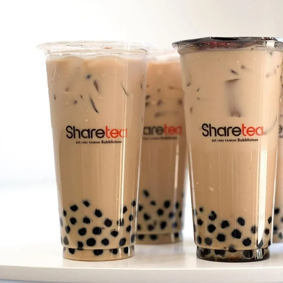 Three cups of milk tea with black tapioca pearls on a white surface