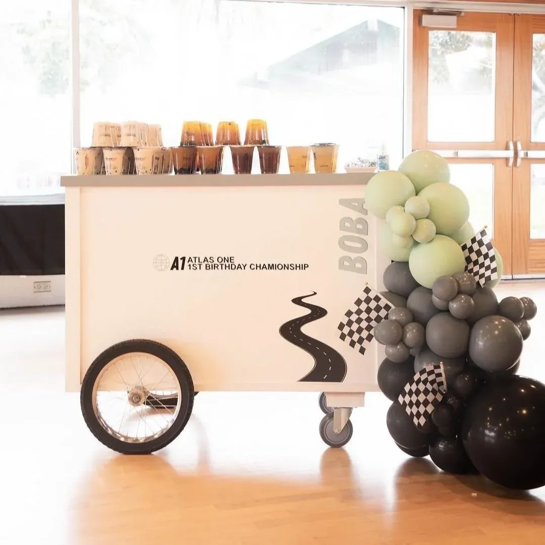 Decorated dessert cart with jars and balloons in black, white, and pale green by a bright window