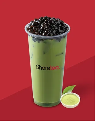 Tall green milk tea with tapioca pearls and a small cup on a red background