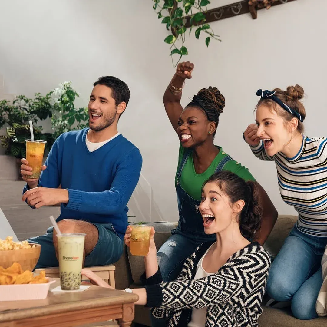 Friends smiling and toasting drinks at a casual indoor gathering