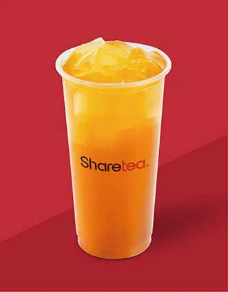 Tall orange frozen drink in a clear plastic cup with a lid, on a red background.