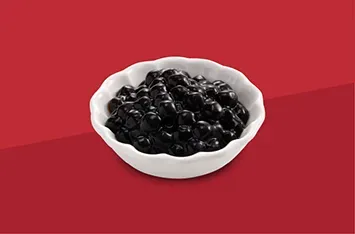 White bowl filled with glossy black beans on a red background