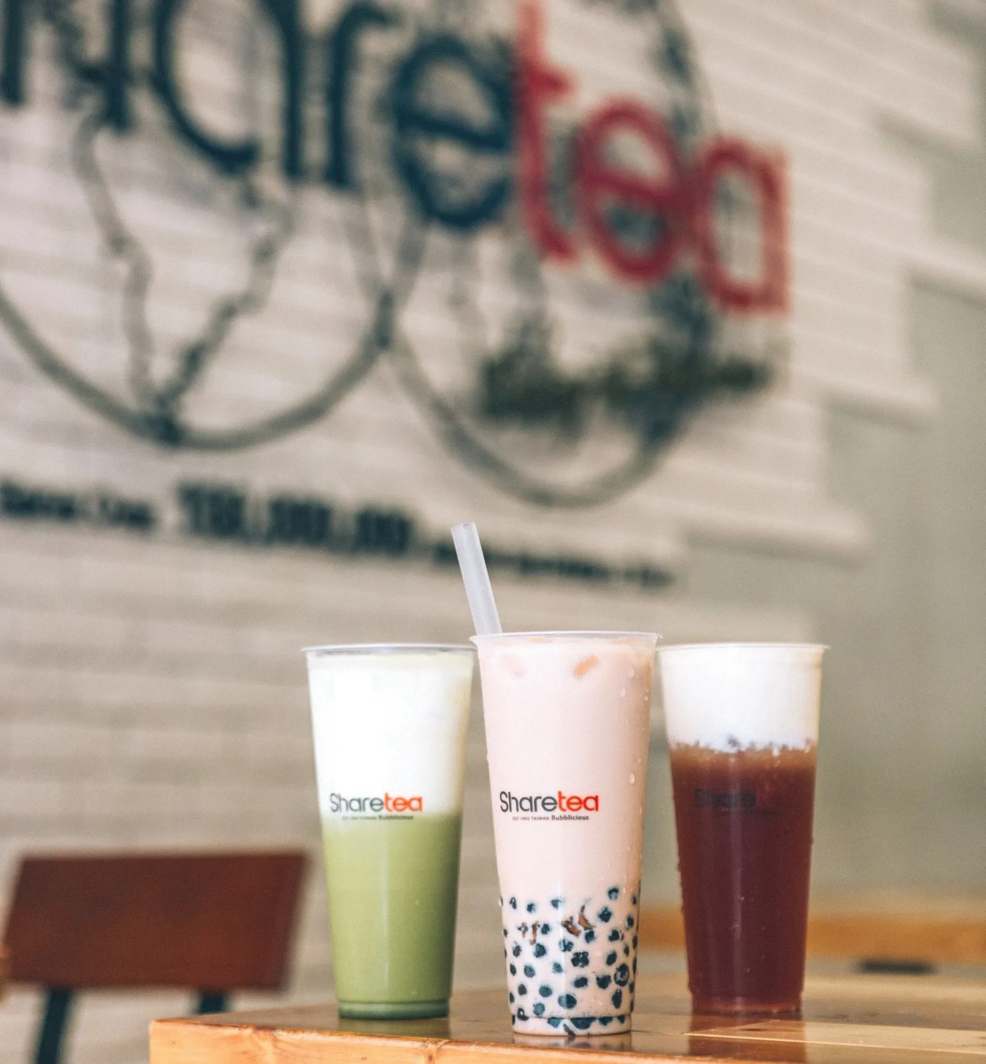 Three bubble tea drinks in green, white, and brown on a table in a cafe