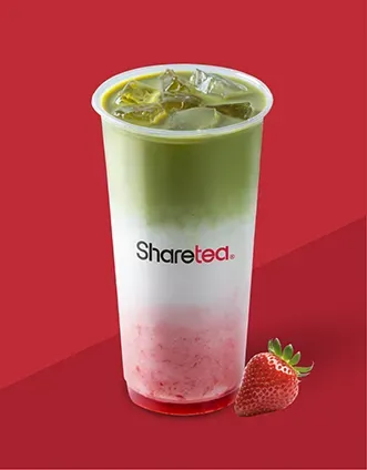 Iced green tea drink with strawberry gradient in a clear cup on a red background, with a strawberry beside it