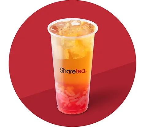 Tall transparent cup of iced orange drink with red fruit base and straw on a red circular background