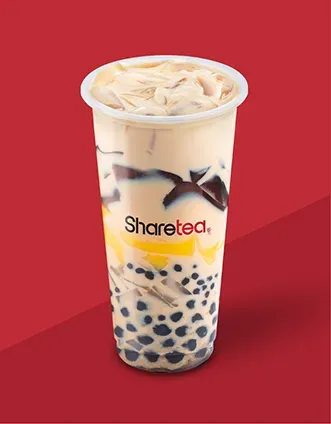 Iced milk tea with tapioca pearls in a clear cup against a red background