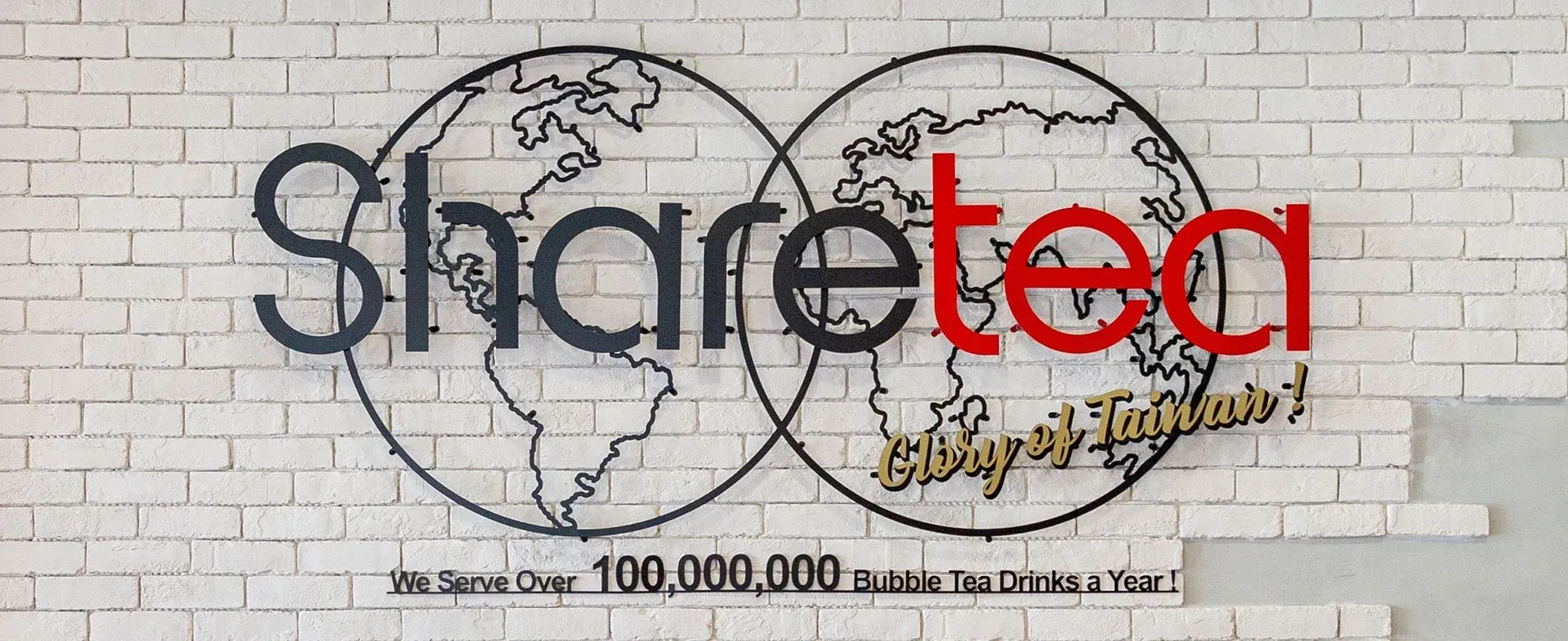 Sharetec logo on a white brick wall, with dark blue and red text over globe outlines.