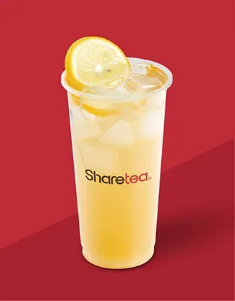 Iced lemon drink in a clear cup with a lemon slice on a red background.