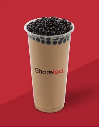 Tall milk tea with black tapioca pearls in a clear cup on a red background.