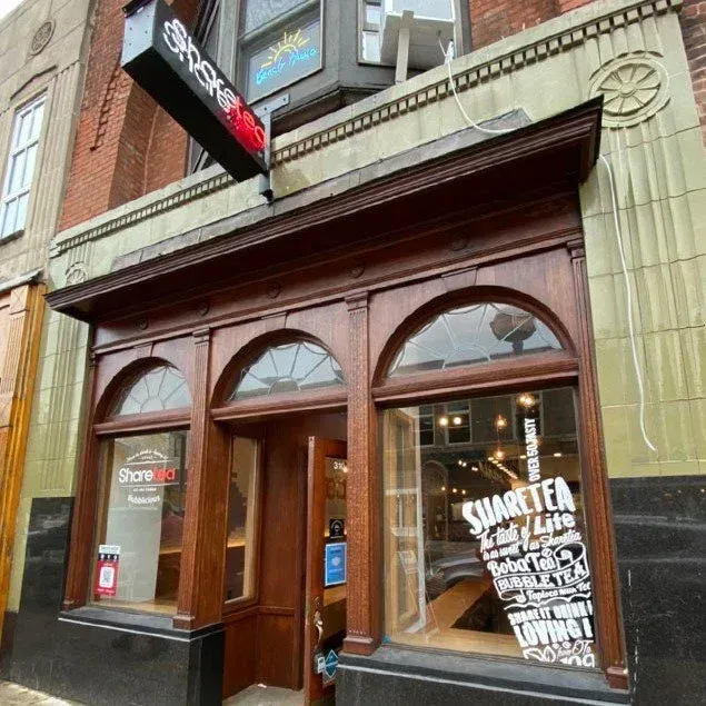 Storefront with wooden facade, arched windows, and a glass door on a city street.