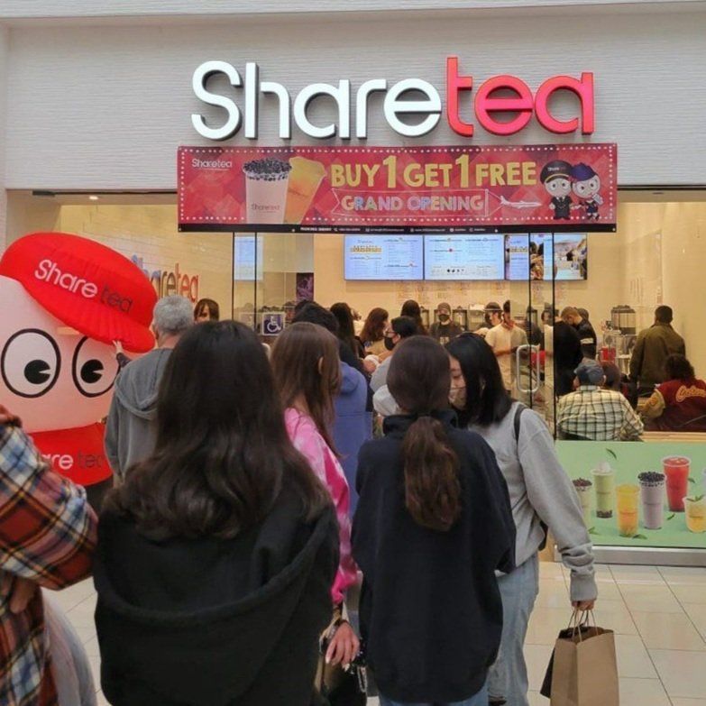 Sharetea store entrance with a “Buy 1 Get 1 Free” grand opening banner and a small crowd outside