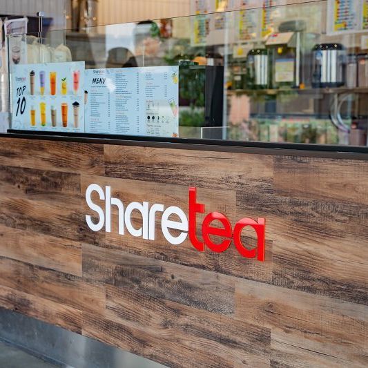 Sharetea café counter with wood paneling and a menu display behind glass