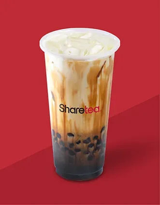 Iced milk tea with black tapioca pearls in a clear cup on a red background