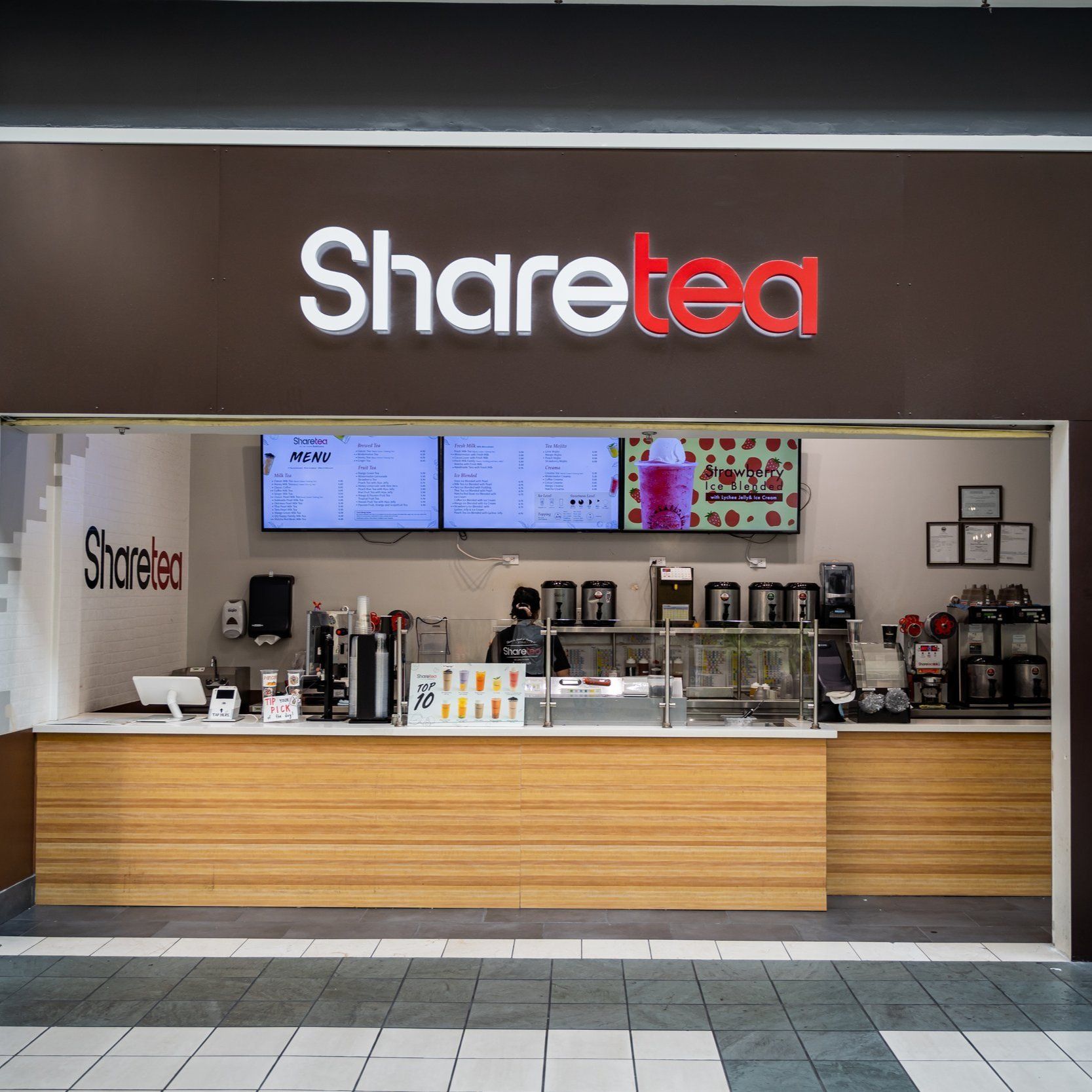 Sharetea café storefront with menu screens, drink display, and wooden counter in a mall kiosk