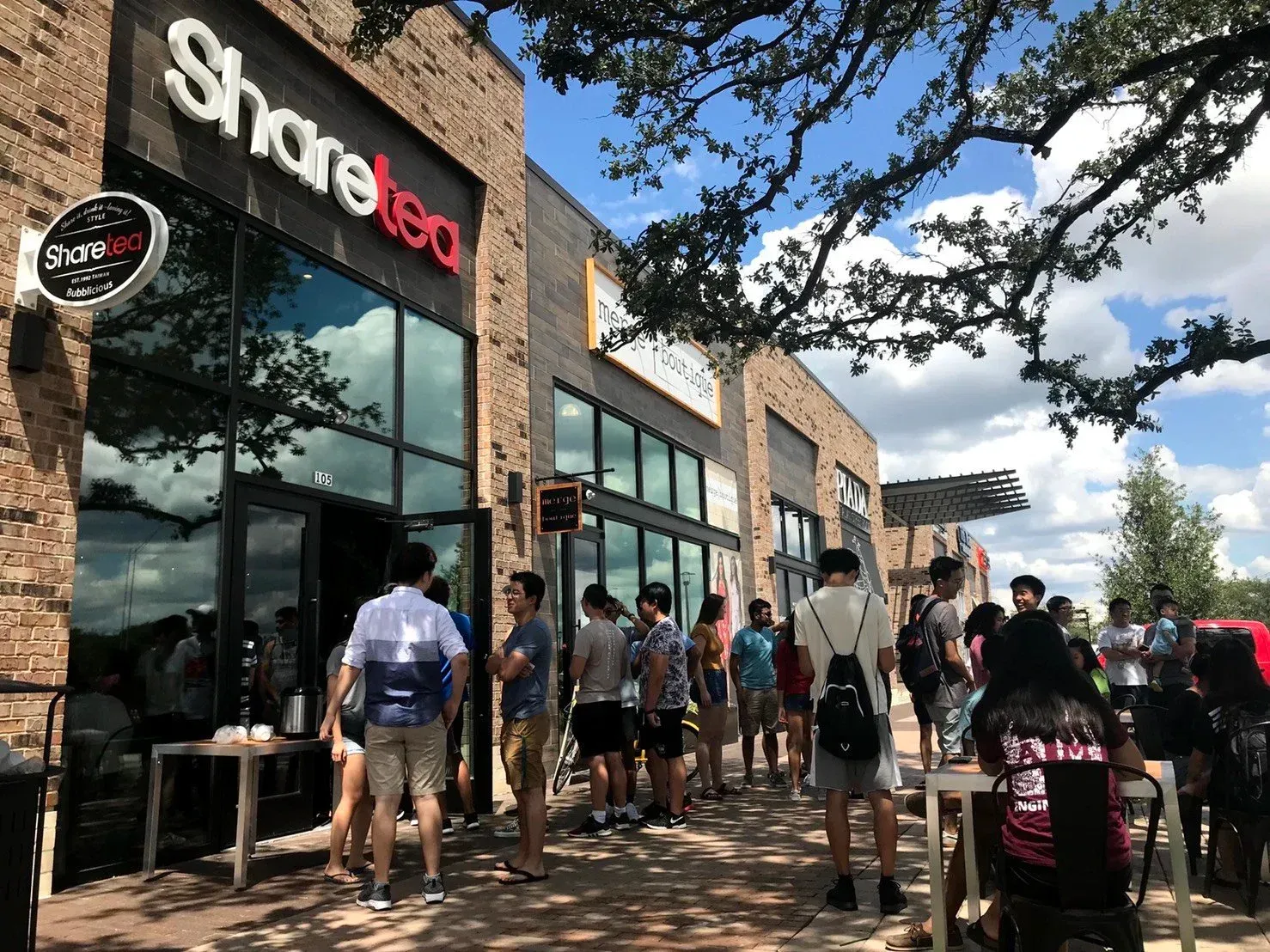People waiting outside a Sharetea storefront on a sunny day