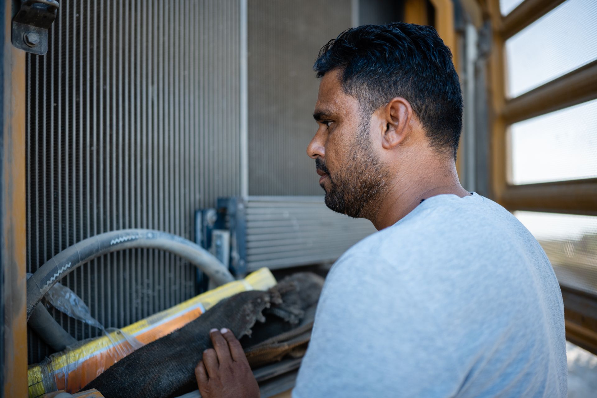 A technician inspecting a radiator of heavy equipment on a construction site.