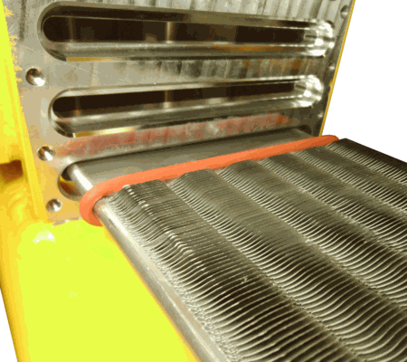 A metal component with corrugated fins partially inserted into a yellow machine housing, sealed by an orange gasket.