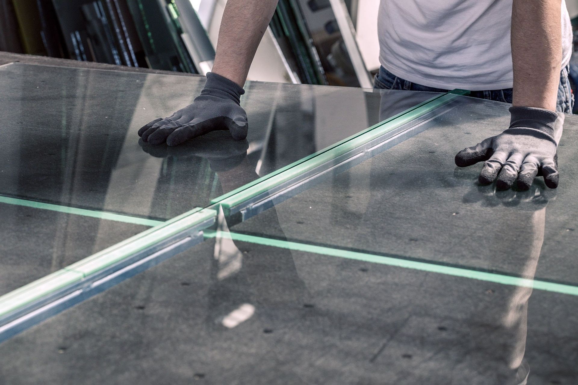 A man is cutting a piece of glass on a table.