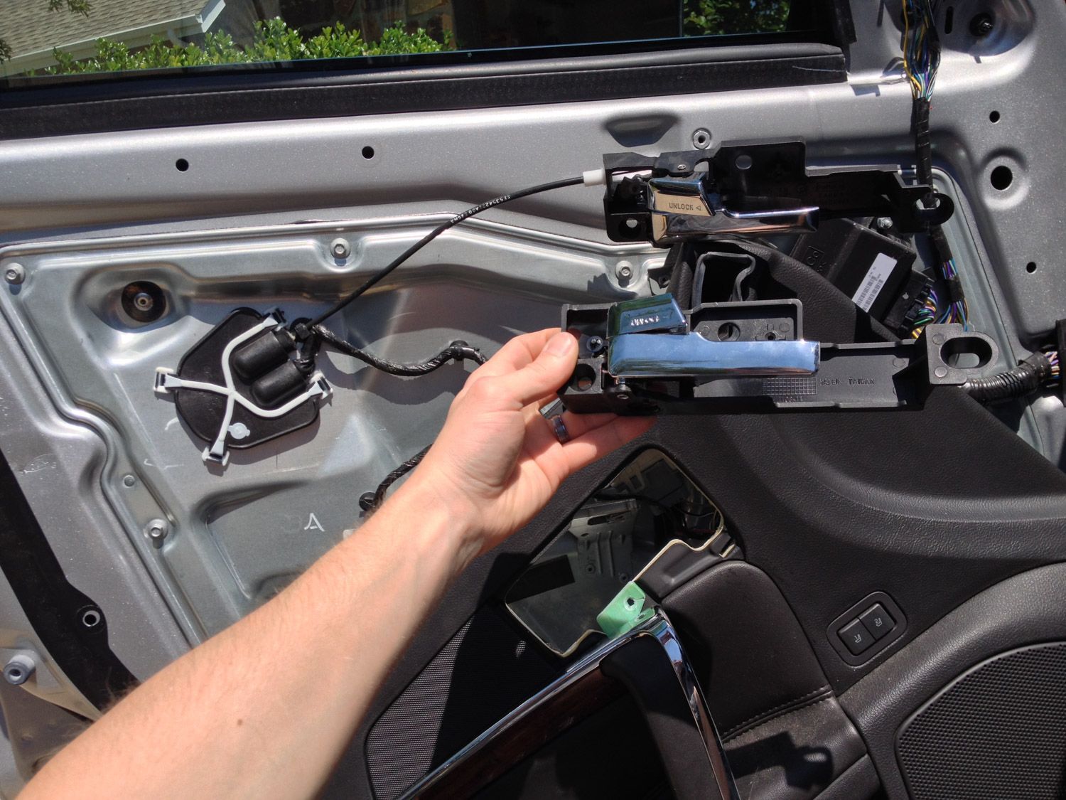 A person is holding the door handle of a car