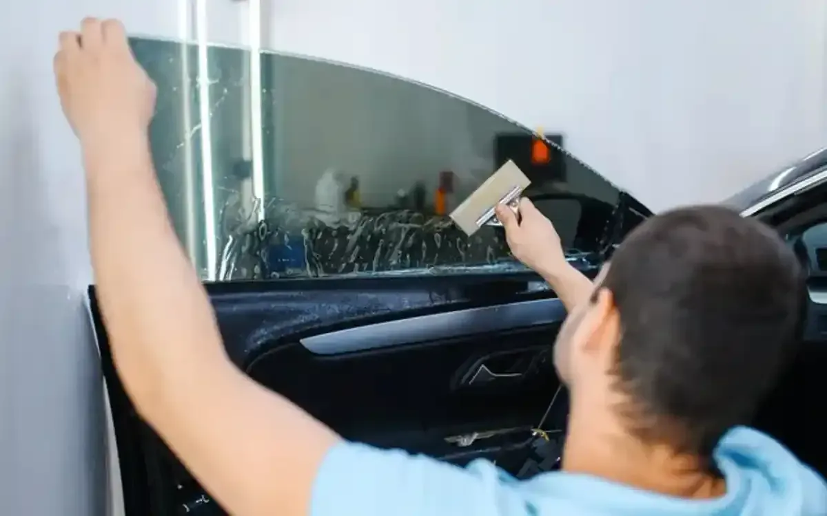 A man is applying window tinting to a car window.
