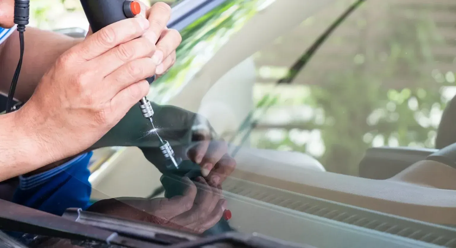A man is fixing a cracked windshield on a car.
