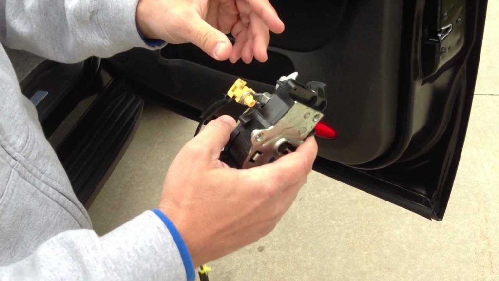 A person is holding a piece of metal in their hands in front of a car door.