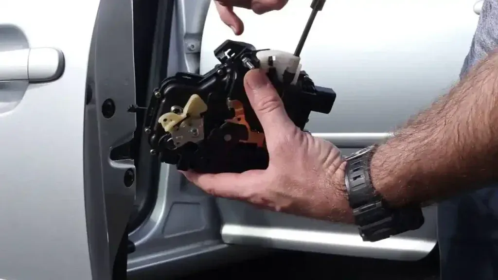Man holding a car door lock mechanism in front of an open car door.