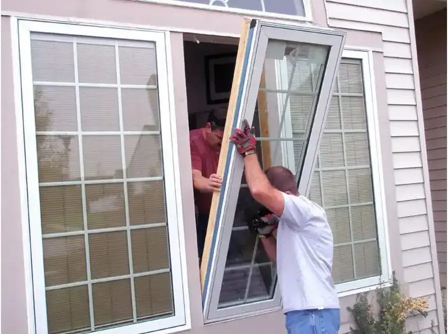 Two men are installing a window on a house