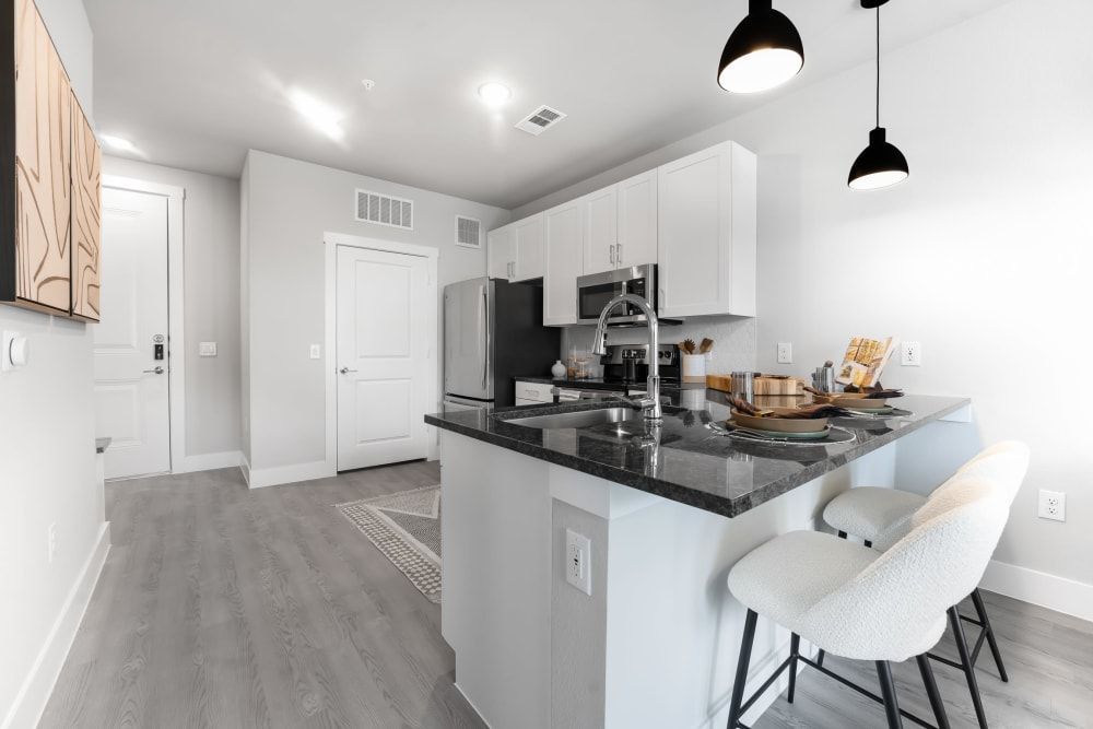 A kitchen with white cabinets and a black counter top at The Bennett, which offers apartments in South Austin, TX.