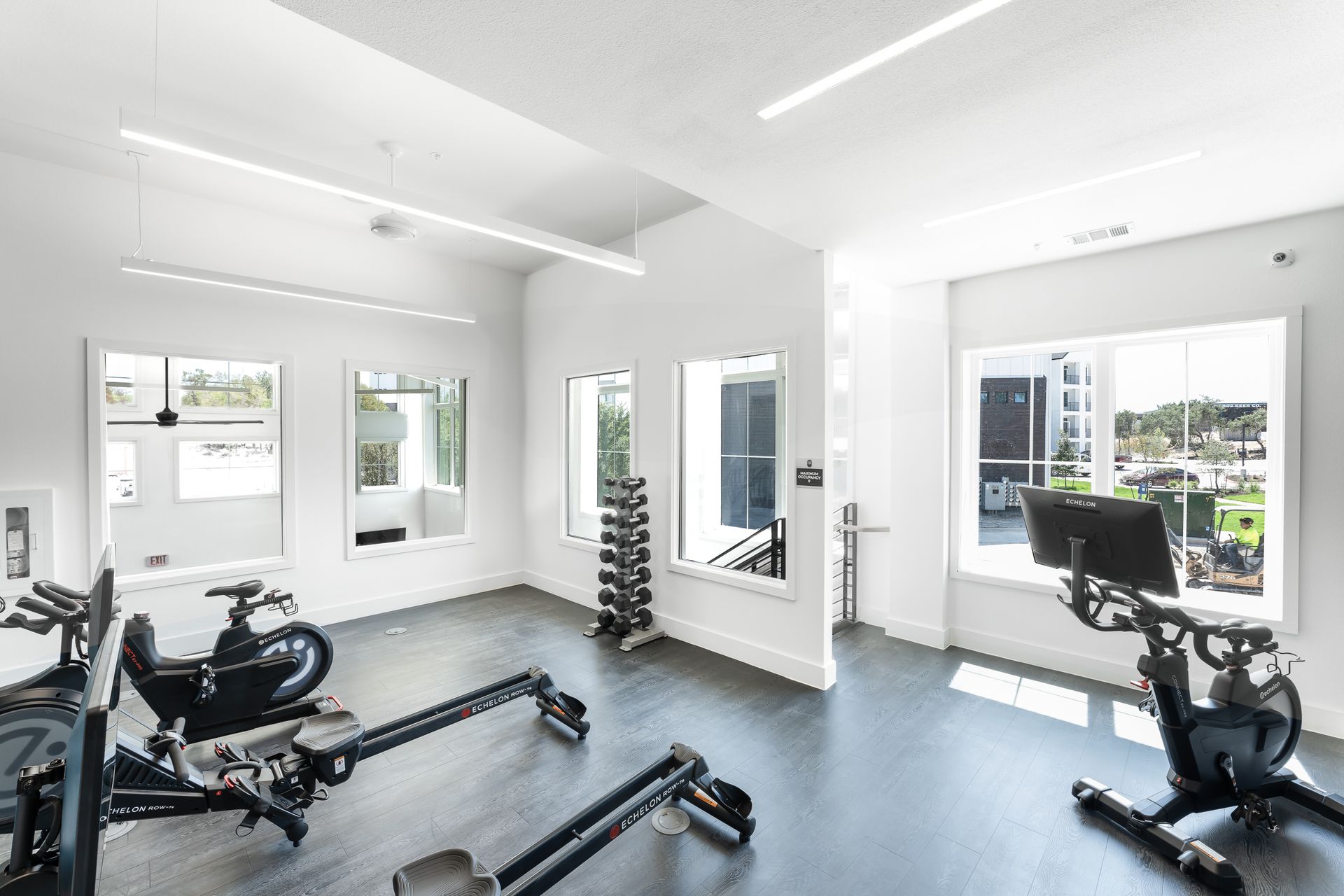 A gym with a lot of exercise equipment and a lot of windows at The Bennett, which offers apartments for rent in South Austin, TX.