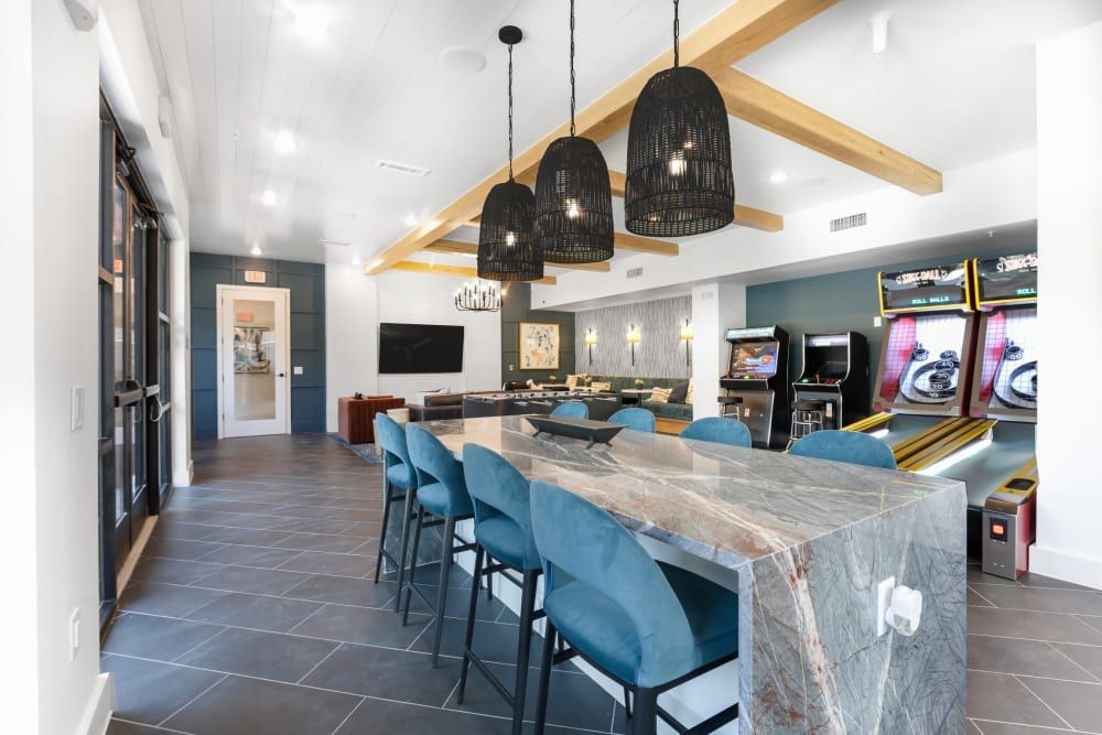A large room with a bar and arcade games at The Bennett, which offers apartments for rent in South Austin, TX.