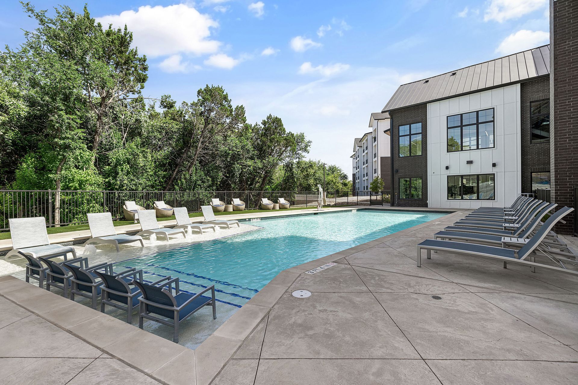 A large swimming pool with a lot of chairs around it at The Bennett, which offers apartments for rent in South Austin, TX.