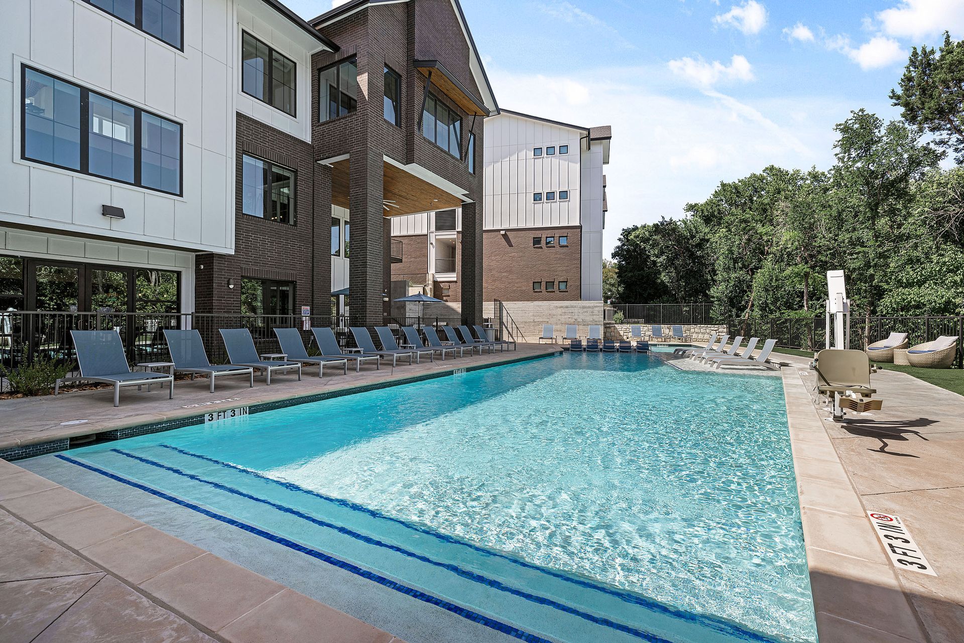 A large swimming pool is surrounded by chairs and a building at The Bennett, which offers apartments for rent in South Austin, TX.