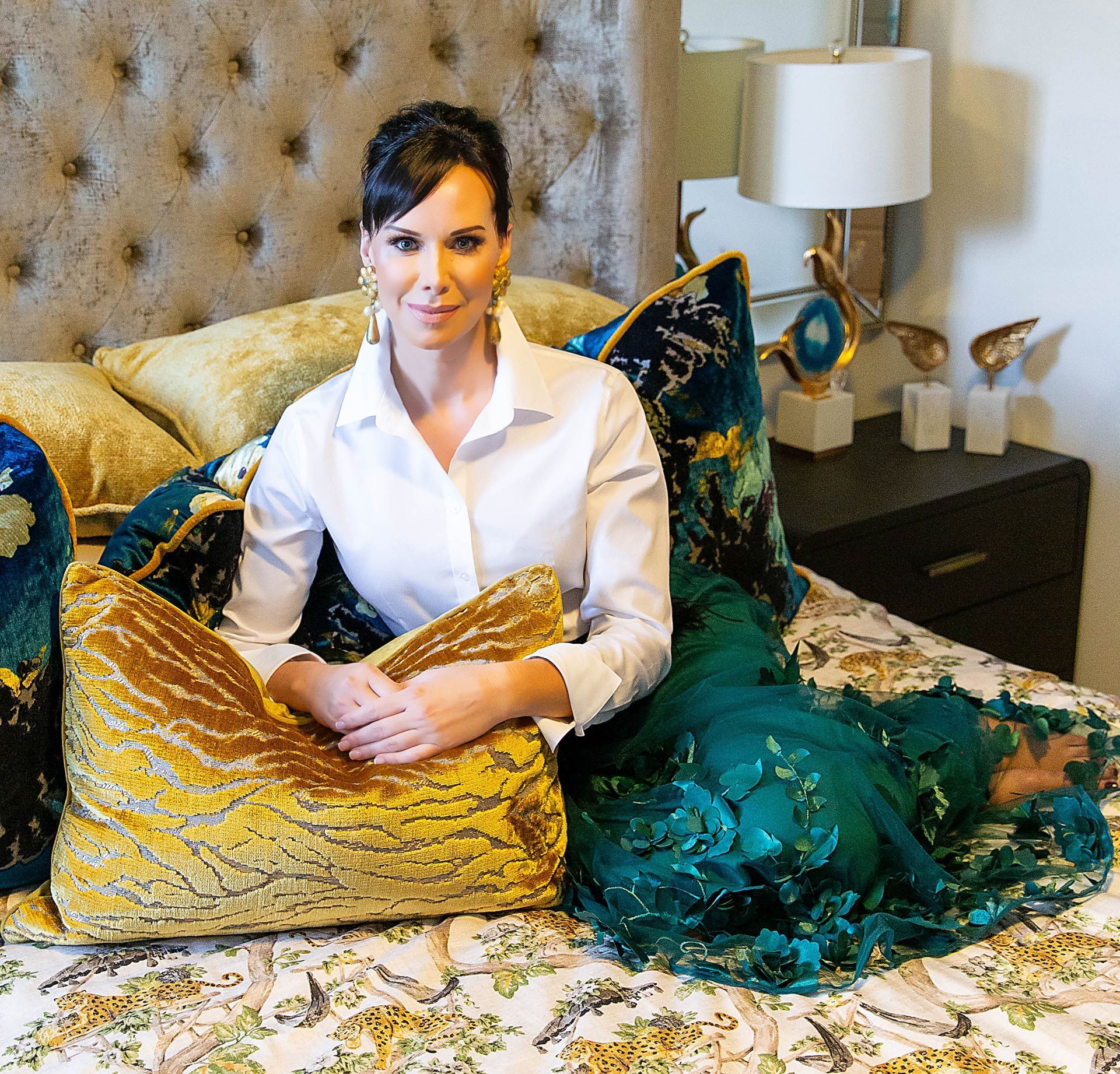 Carrie Riddle Interior Design in a white shirt sits on a bed with pillows