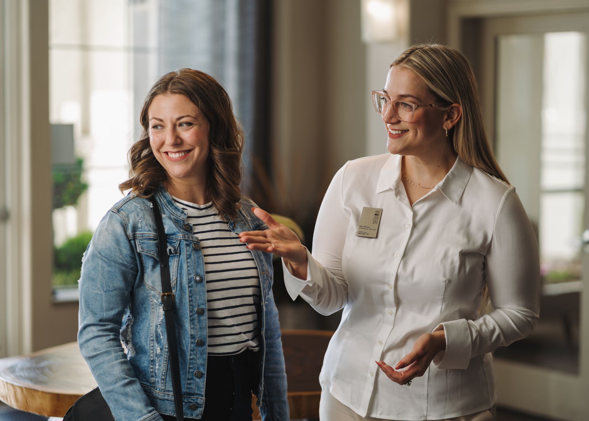 Two women chatting and both smiling Sequoia West Coast Multifamily Property Management.