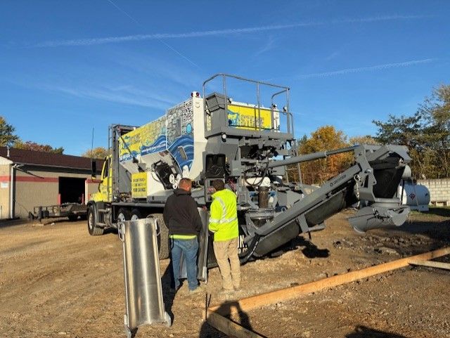 Liquid Stone workers beside a large road milling machine on a sunny construction site